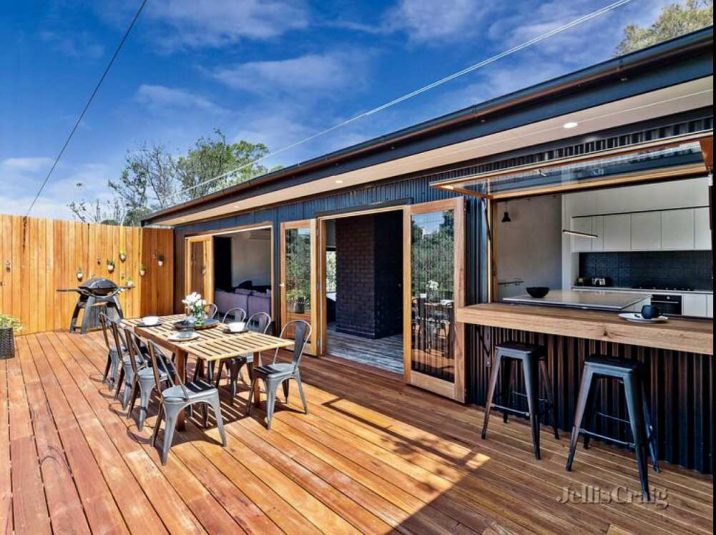 Open indoor outdoor decking area with dining table and chairs.